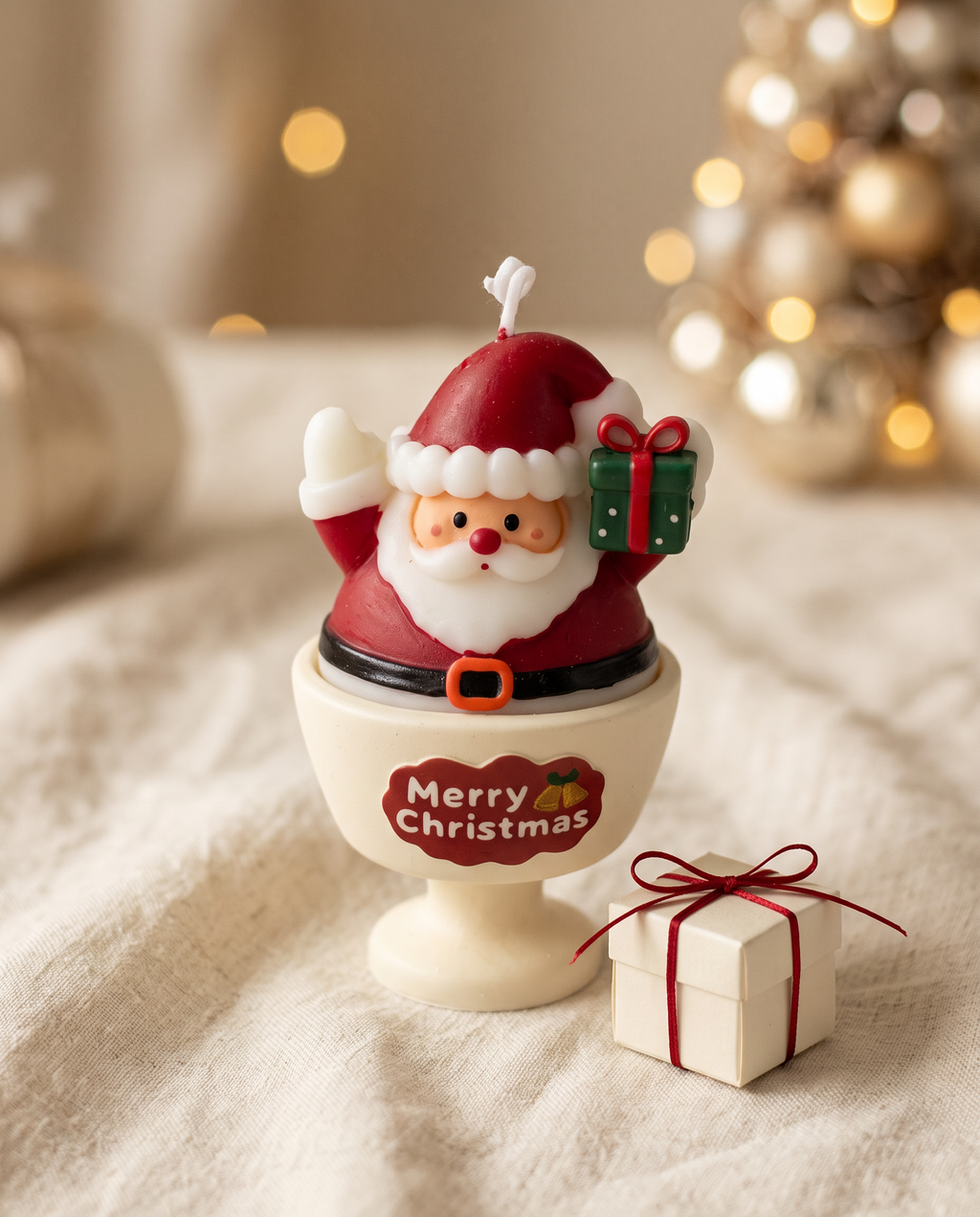 Santa goblet candle styled with a small gift box and red ribbon on a linen throw